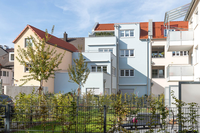 Außenansicht eines mehrstöckigen Wohnhauses, im Vordergrund sieht man einen kleinen Garten.